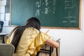 Back view of school girl on lesson in classroom write hardworking on blackboard Royalty Free Stock Photo