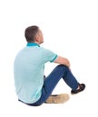 Back view of seated handsome man in polo looking up.
