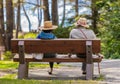Back view of a senior couple wearing hats sitting on a wooden bench in the park. Reationship. Vancouver Island, BC Royalty Free Stock Photo