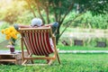 Back view of senior man with white hat sitting on garden chair and by the table in garden. Summer vacation in green surroundings. Royalty Free Stock Photo