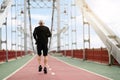 Back view senior sportsman jogging by city bridge, copy space Royalty Free Stock Photo