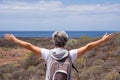 Back view of senior woman traveler enjoying outdoors trekking, looking at horizon over sea with open arms Royalty Free Stock Photo