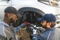 back view of servicemen working on a car wheel and changing it, car workshop Royalty Free Stock Photo