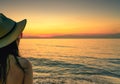 Back view of woman watching sunset at the beach. Woman wear sunglasses and straw hat relaxing at tropical paradise beach. Royalty Free Stock Photo