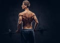 Back view of shirtless man with stylish hair and muscular ectomorph doing the exercises with the barbell. Royalty Free Stock Photo