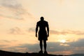 Back view on silhouette of bodybuilder posing at the sunrise or sunset in mountains. Handsome strong man showing his Royalty Free Stock Photo