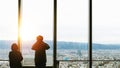 Back view of silhouette couple tourist traveler looking beautiful building cityscape on top near window glass