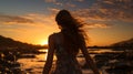 Back view silhouette of a girl standing in the water on a beach as the sunset Royalty Free Stock Photo