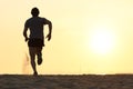 Back view silhouette of a runner man running on the beach