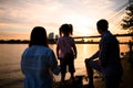 Back view on silhouettes of family couple with child stay on the sandy river bank