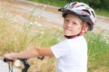 Back view of small boy in protective helmet riding bicycle in park on summer day. Weekend activity. Royalty Free Stock Photo
