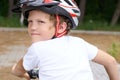 Back view of small boy in protective helmet riding bicycle in park on summer day. Weekend activity. Royalty Free Stock Photo