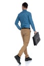 Back view of smart casual man walking and holding suitcase Royalty Free Stock Photo