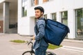 Back view of smiling handsome young delivery man in protective helmet posing standing near bicycle in city street on Royalty Free Stock Photo