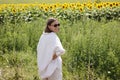 Back view of smiling satisfied beautiful young woman with short hair in sunglasses walking at large bright sunflowers Royalty Free Stock Photo