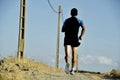 Back view sport man running on countryside track with power line poles Royalty Free Stock Photo