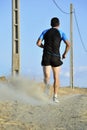 Back view sport man running on countryside track with power line poles Royalty Free Stock Photo