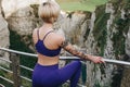 back view of sportswoman in stylish sportswear posing on cliff near railings Royalty Free Stock Photo