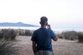 Back view of standing man using mobile phone making phone call in outdoor against a travel scenic destination background with Royalty Free Stock Photo