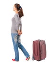 Back view of standing young traveling brunette woman with suitca