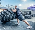 Back view of strong muscular fitness man moving large tire in street gym. Concept lifting, workout training Royalty Free Stock Photo