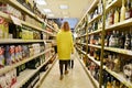 Back view of a stylish woman walking in a supermarket and buying products. Shopping in a supermarket. Woman walks with her