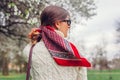 Back view of stylish woman walking with red hair scarf in spring park. Retro female fashion. Headscarf for bun hairstyle Royalty Free Stock Photo