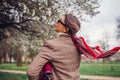 Back view of stylish woman wearing red hair scarf in spring park. Retro female fashion. Headscarf for bun hairstyle Royalty Free Stock Photo