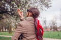 Back view of stylish woman wearing red hair scarf in spring park. Retro female fashion. Headscarf for bun hairstyle Royalty Free Stock Photo