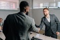 Back view of successful African-American and Caucasian businessmen in business suits shaking hands after successful Royalty Free Stock Photo