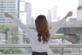 Back view of successful young Aian business woman raising her hands at urban building city background. Royalty Free Stock Photo