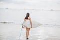 back view of surfer with surfboard walking on beach Royalty Free Stock Photo