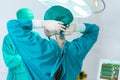 Back view of surgeon tying surgical cap in preparation, Medical team performing surgical operation in operating room, Team surgeon