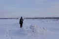 Back view of tall warmly dressed man walking on icy beach with couple in soft focus background