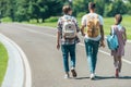 back view of teenage students with backpacks walking together