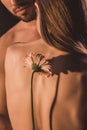 back view of tender couple hugging and holding gerbera flower,