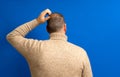 Back view of thoughtful man scratching his head over blue background. He wonders why he doesn't have luck in life Royalty Free Stock Photo