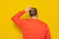 Back view of thoughtful man scratching his head over yellow background. He is doubting his existence, he does not Royalty Free Stock Photo