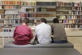 Back view of three adult friends sitting on a sofa in the library. Ferrara, Italy