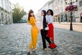 Back view of three diverse young female laughing friends, wearing stylish colorful clothes, walking arm in arm together Royalty Free Stock Photo