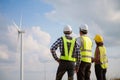 Back view of three engineers discussing and checking turbines on wind turbine farm. Renewable energy technology and sustainability Royalty Free Stock Photo