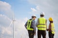 Back view of three engineers discussing and checking turbines on wind turbine farm. Renewable energy technology and sustainability Royalty Free Stock Photo