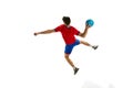 Back view. Throwing ball in a jump. Young man, professional handball player in red uniform playing, training isolated