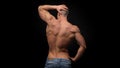 The back view of torso of attractive male body builder on dark background.