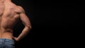 The back view of torso of attractive male body builder on dark background.