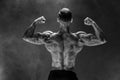 Back view of Unrecognizable man, strong muscles posing with arms down in smoke. Royalty Free Stock Photo