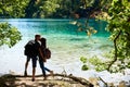 Back view of tourist couple boy and girl with backpacks standing on river bank Royalty Free Stock Photo