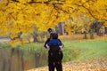 Back view of tourist young man using camera taking a picture at Autumn fall trees Royalty Free Stock Photo