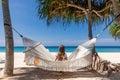 Back View of Travel Woman Sitting on White Hammock on Sandy Beach Royalty Free Stock Photo