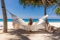 Back View of Travel Woman Sitting on White Hammock on Sandy Beach Royalty Free Stock Photo